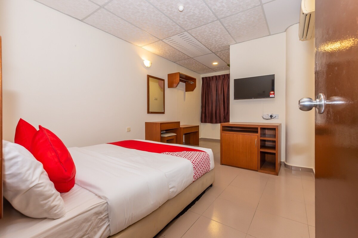 A hotel room with a bed, a desk, a TV, and a wardrobe.