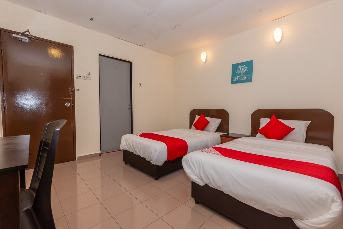 A hotel room with two beds, a desk, and a chair.