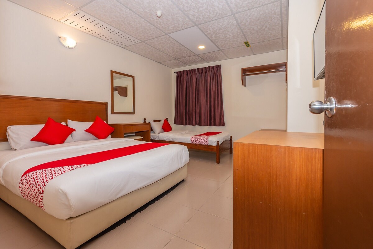 A hotel room with two beds, a wooden headboard, a nightstand, a mirror, and a door.