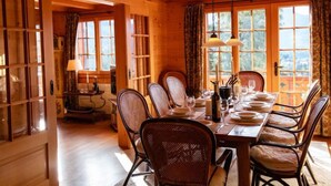 Comedor de madera con una mesa grande dispuesta para seis personas, rodeada de sillas de mimbre.