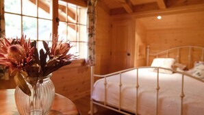 Habitación de cabaña de madera con una cama y un jarrón con flores sobre una mesa.