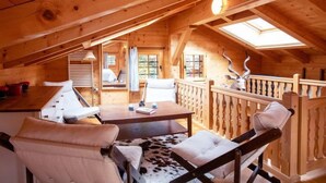 Una cabaña de madera acogedora con un dormitorio en el altillo, zona de comedor y balcón con un adorno de cabeza de venado.