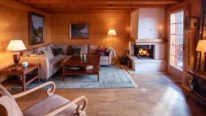 Interior acogedor de una cabaña de troncos con chimenea, paredes de madera, un sofá y una mesita de centro.