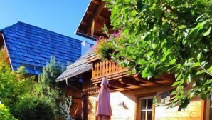 A wooden cabin with a deck, a barbecue grill, and a picnic table.