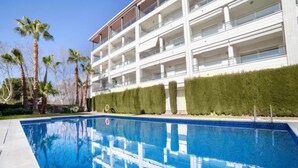 A modern hotel with a pool, multiple balconies, and palm trees. - Nautic Par by Interhome (Playa de Aro)