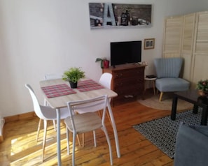 Un comedor con una mesa, sillas, un televisor, un aparador y una silla azul.