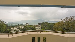 Un balcón con vistas a un edificio histórico y vegetación circundante.