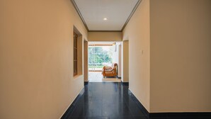 Un pasillo con piso de baldosas negras, paredes color beige y un banco de madera al final.