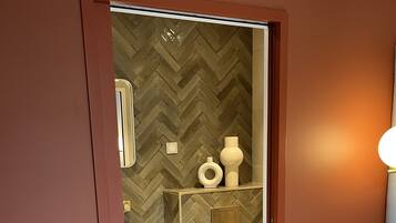 A hotel room with a bed, a bathroom with a herringbone-patterned wall, a white sink, and a toilet.
