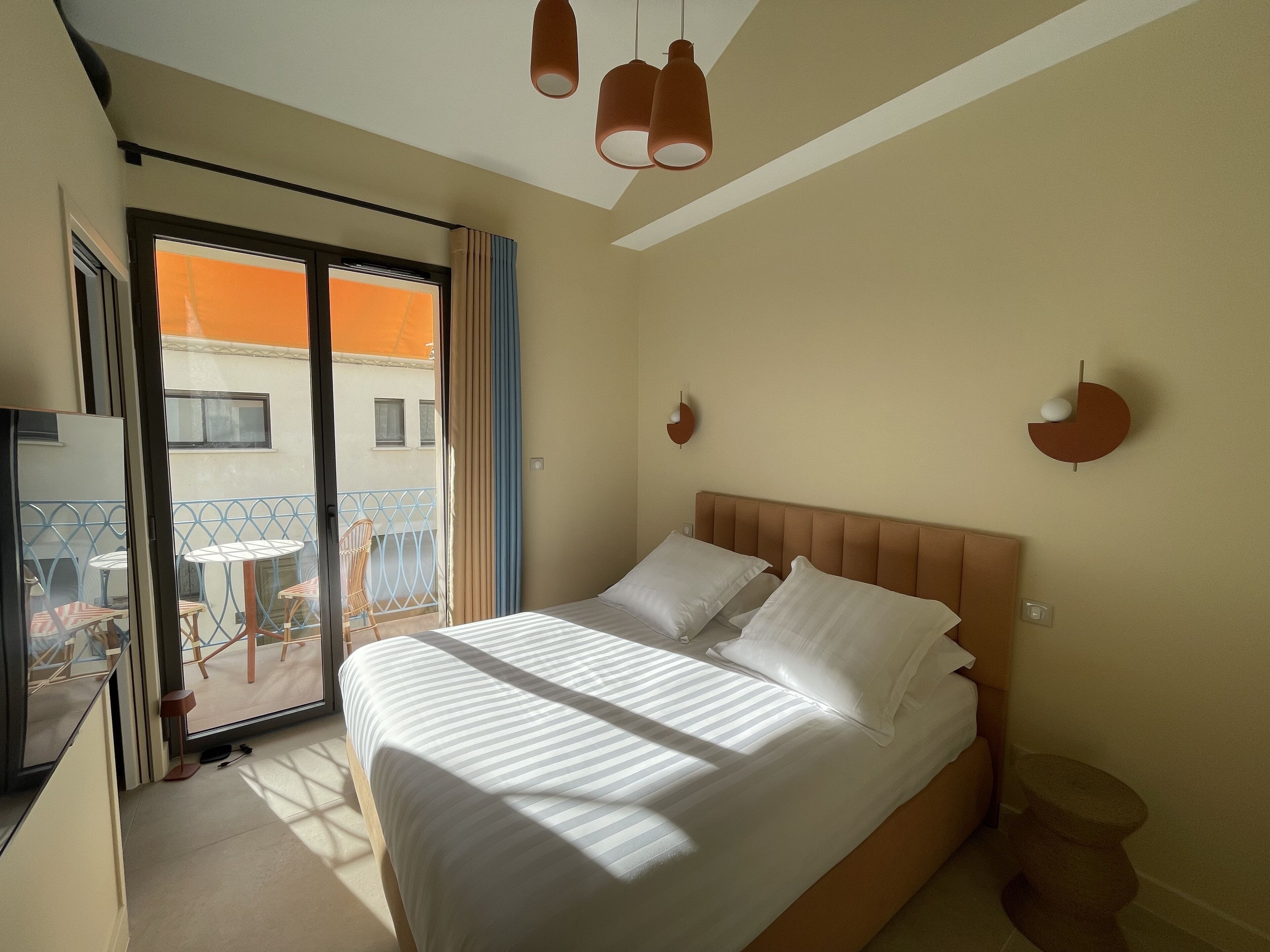 Habitació d'hotel amb un llit, una taula petita i una cadira davant la finestra.