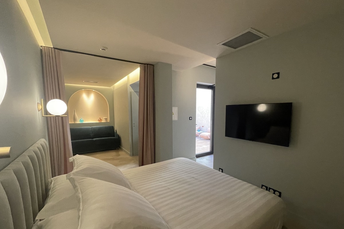 Habitación de hotel moderna con una cama grande, un televisor de pantalla plana en la pared y vistas al área exterior a través de una puerta corrediza.