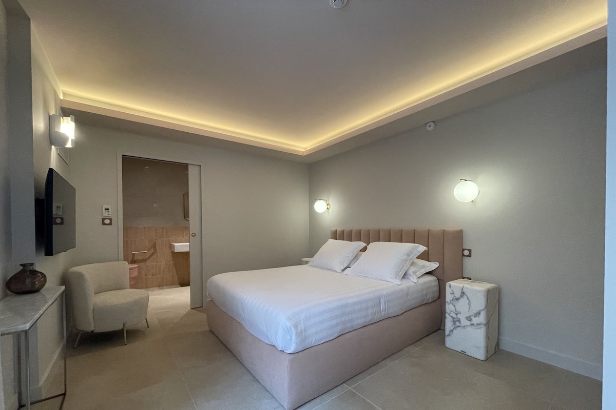 Un dormitorio moderno con una cama grande, mesitas de noche, un escritorio y una silla.