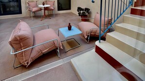 Um espaço amplo em ambiente interno com escada, área de estar e um vaso de planta.