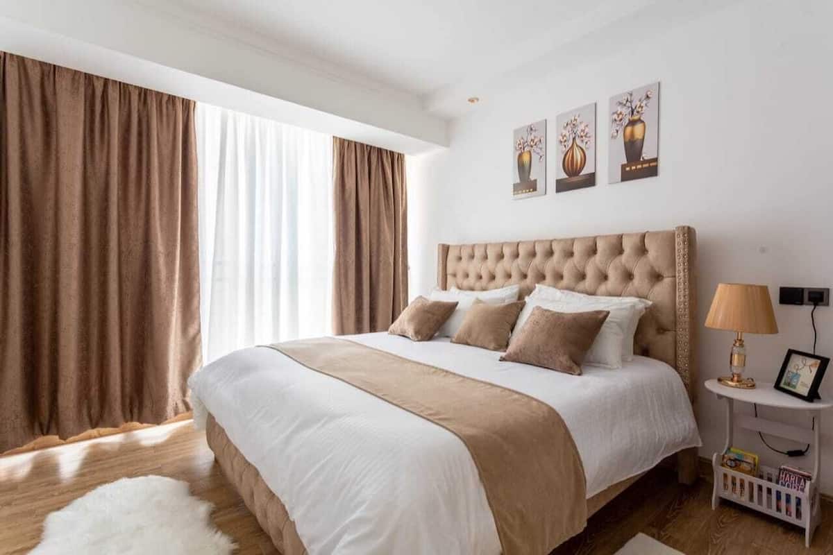 Ein Schlafzimmer mit einem großen Bett, einer weißen Wand und einem Fenster mit Vorhängen.