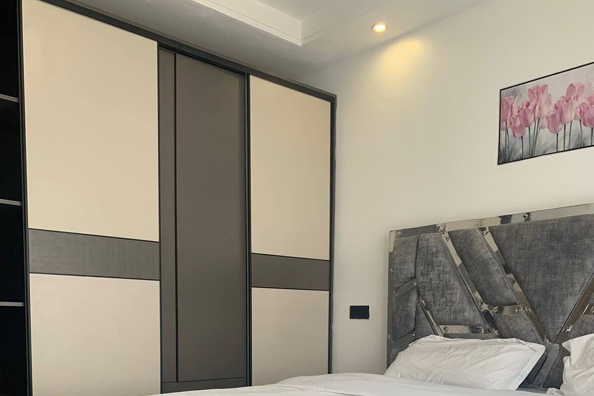 Ein modernes Schlafzimmer mit einem großen Bett, einem grauen Kopfteil und einem Schiebekleiderschrank.