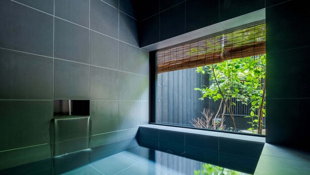 Une salle de bain moderne dotée d’une grande fenêtre, de carreaux foncés et d’un design minimaliste.