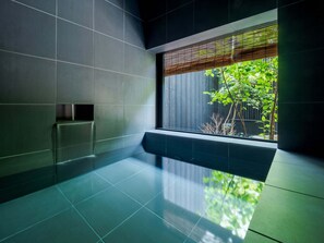 Een moderne badkamer met een groot raam, donkere tegels en een minimalistisch design.
