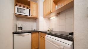 Eine kleine Küche mit Holzausstattung, einer Mikrowelle, einer Kaffeemaschine und einem Geschirrspüler.