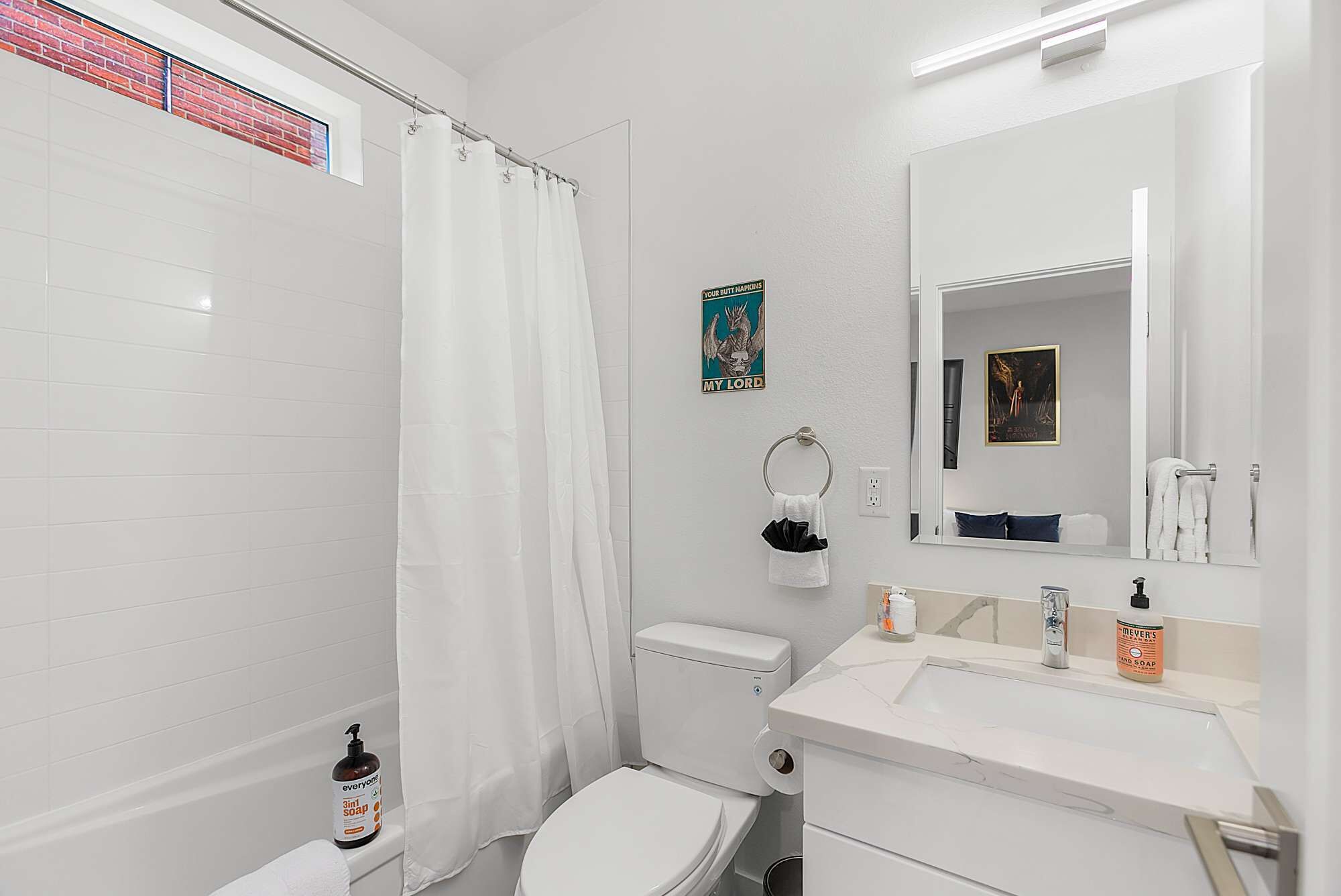 Ein Badezimmer mit Toilette, Duschvorhang, Waschbecken mit Spiegel und Handtuchhalter.