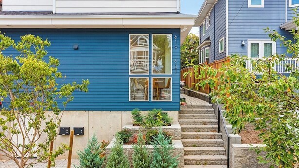 A blue house with a front porch, a set of steps leading to the entrance, and a small garden area with various plants. - Meleys' Crimson Keep: Driftmark's Suite (Seattle)