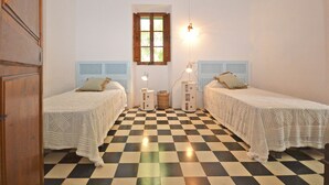 A room with two beds, checkered floor, white walls, wooden window frame, and a hanging light fixture. - Teresa - beautiful house 150 meters from the beach (Alcúdia)