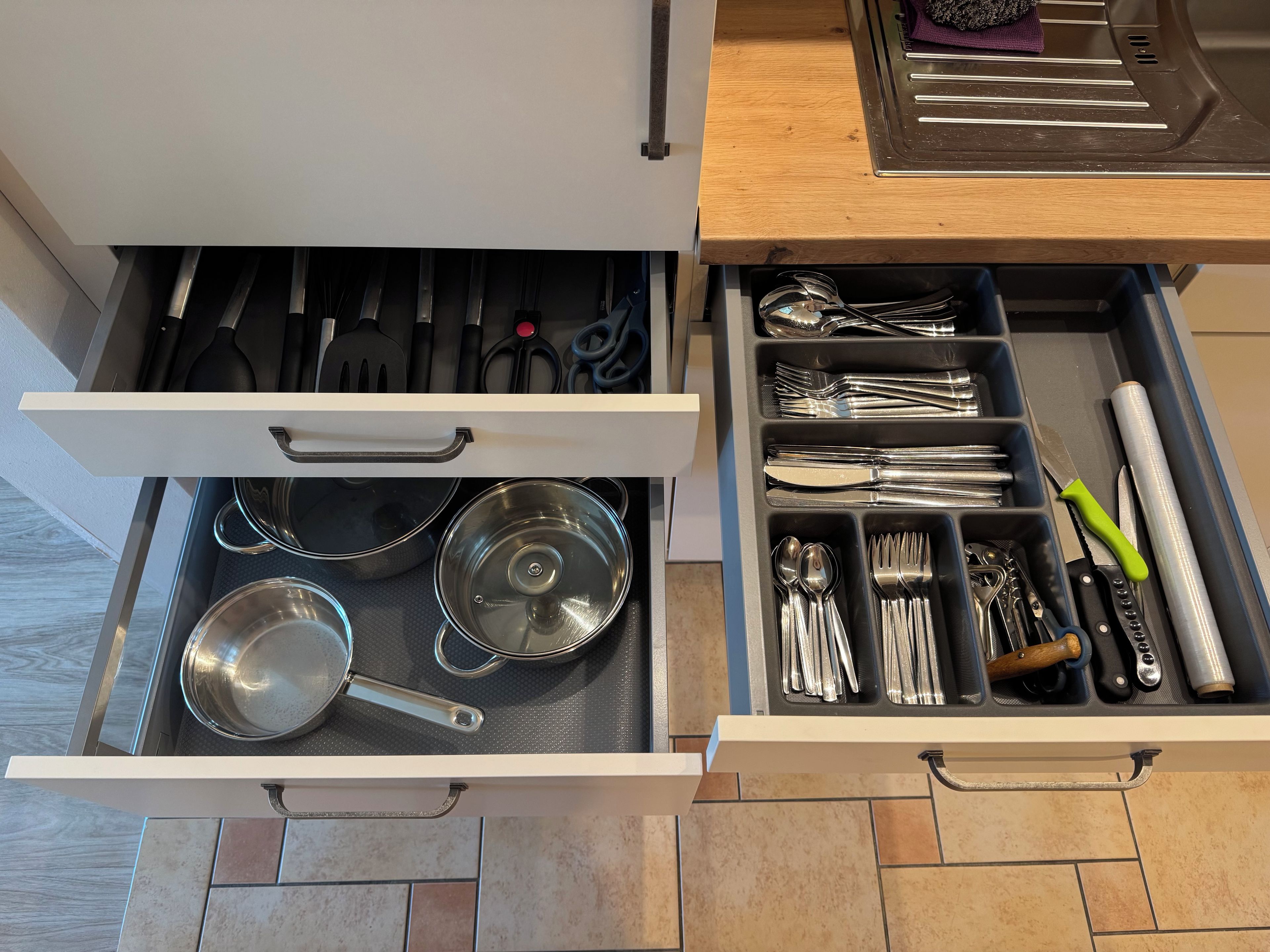 A kitchen drawer with utensils and cookware.