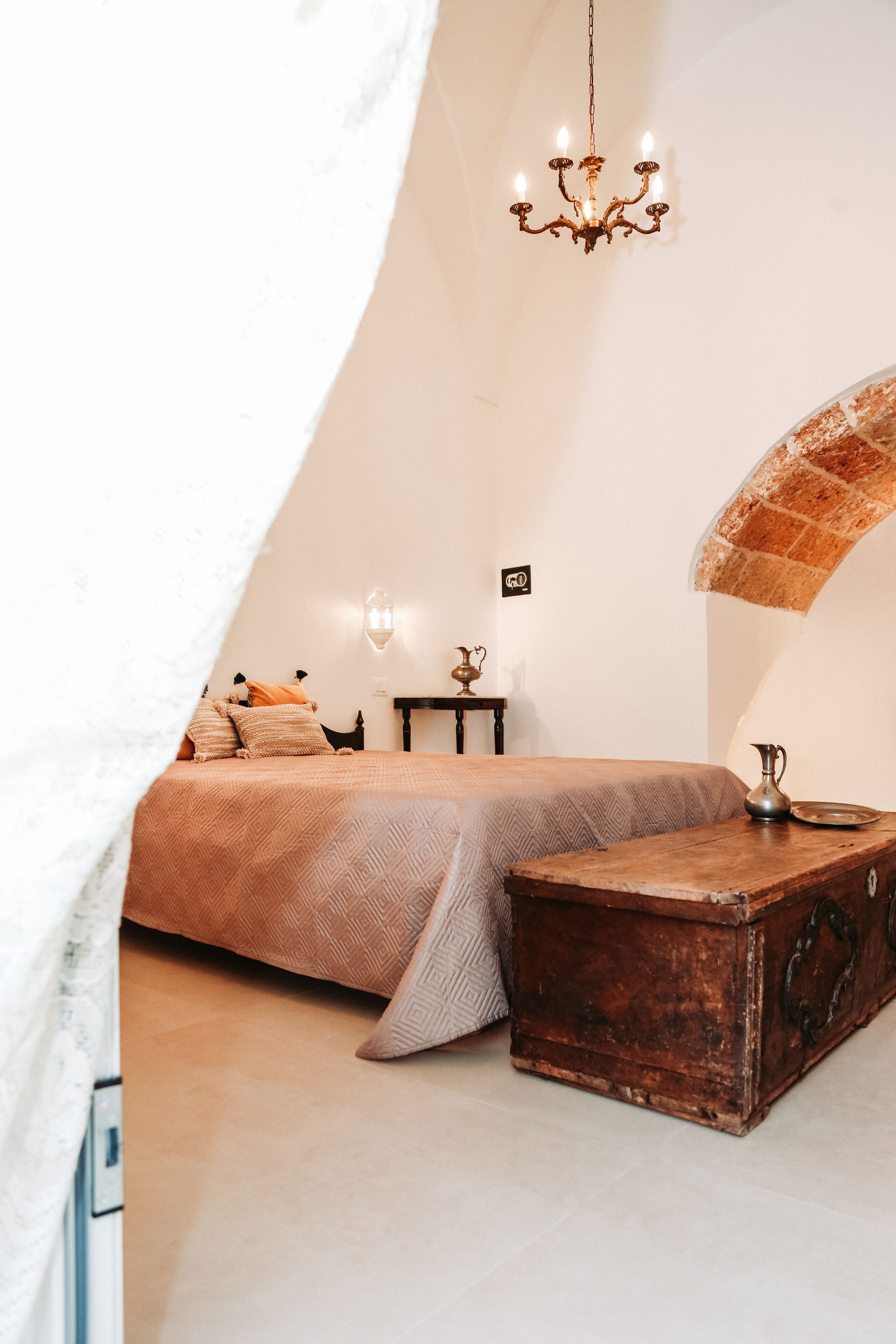 Un'accogliente camera da letto con un letto, un comò, una lampada e un lampadario.