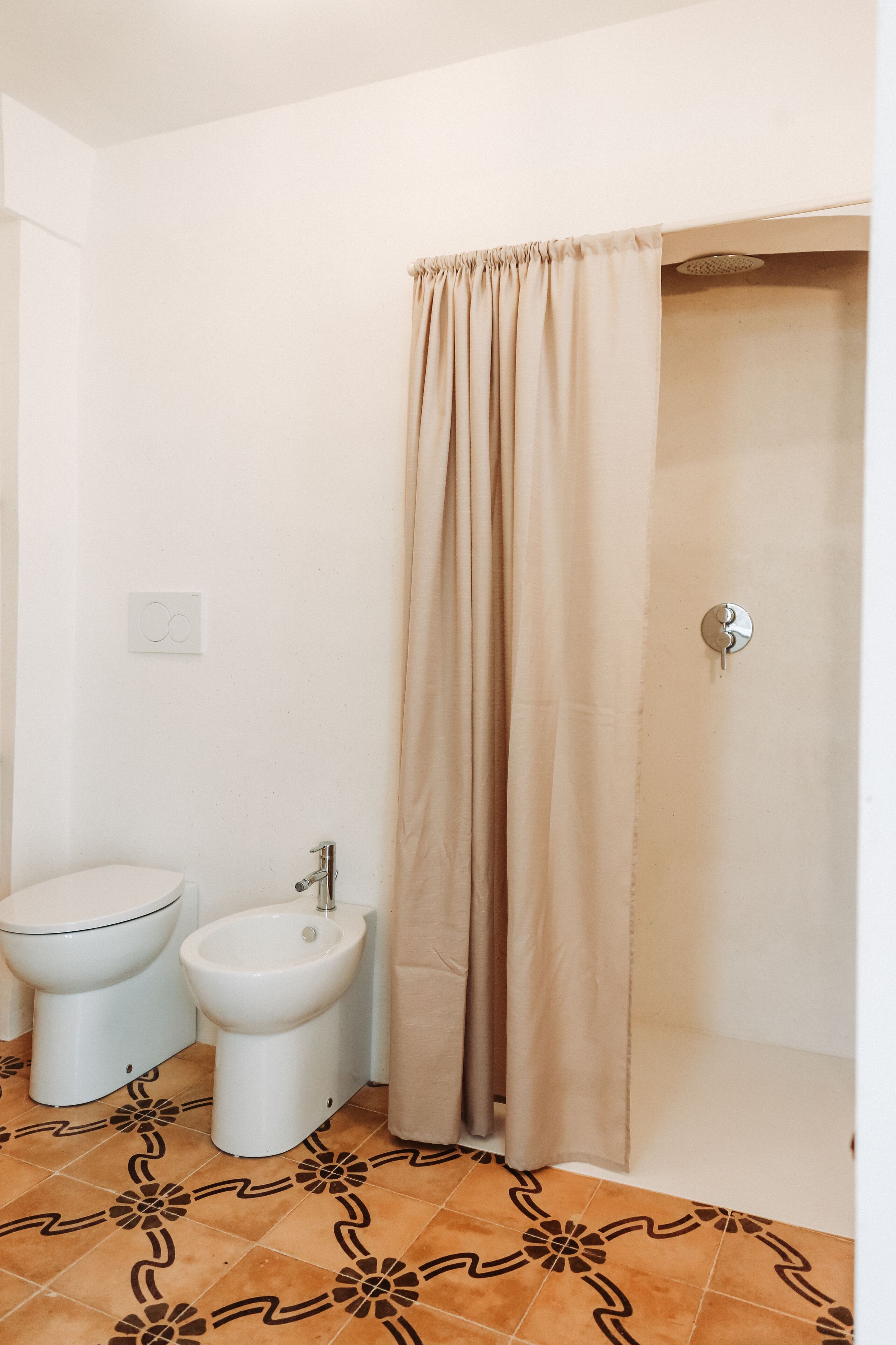 A bathroom with a toilet, bidet, and shower curtain.