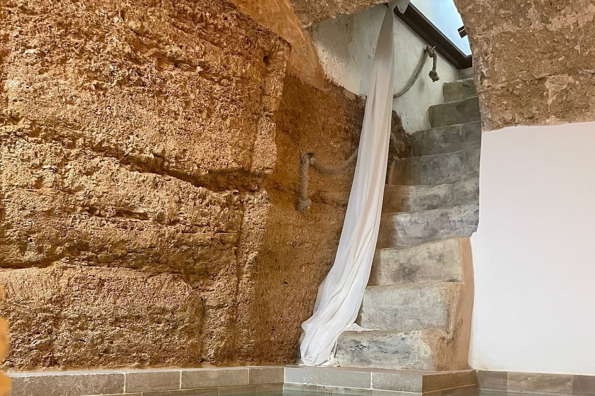 A swimming pool with a stone wall backdrop and a white curtain.