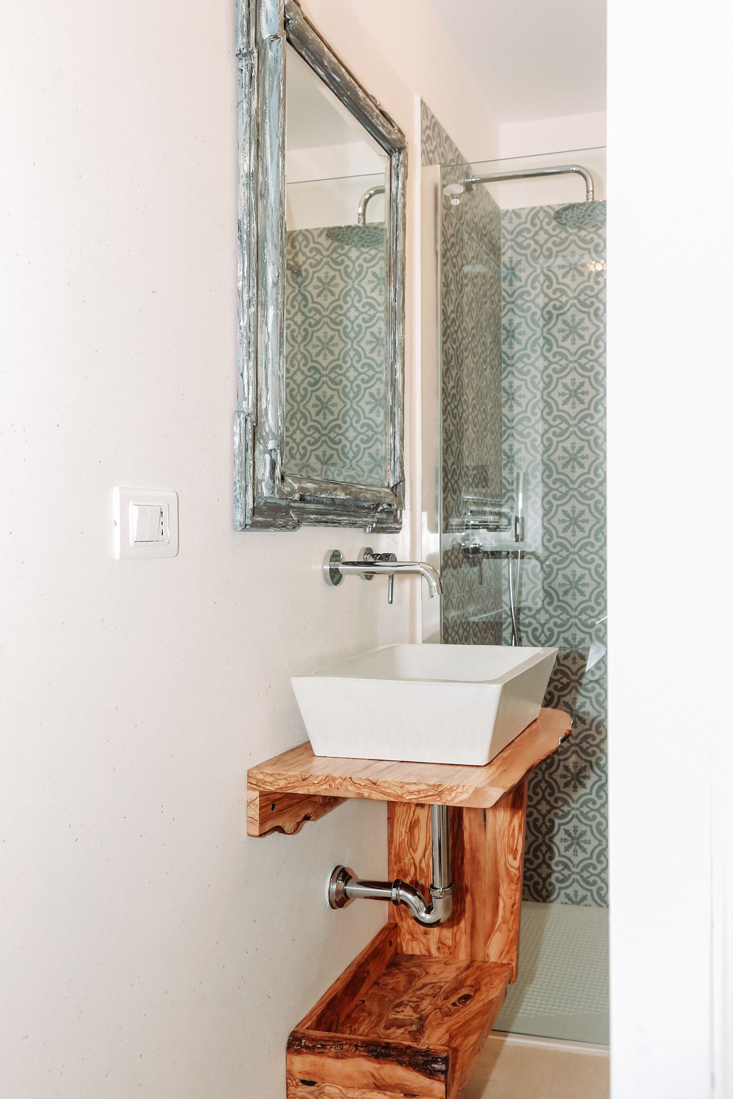 Un baño con lavamanos blanco, tocador de madera y un espejo.