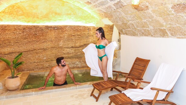 A stone-walled indoor pool area with wooden lounge chairs and a potted plant. - Corte Largo Lauro Dimore&Spa (Ugento)