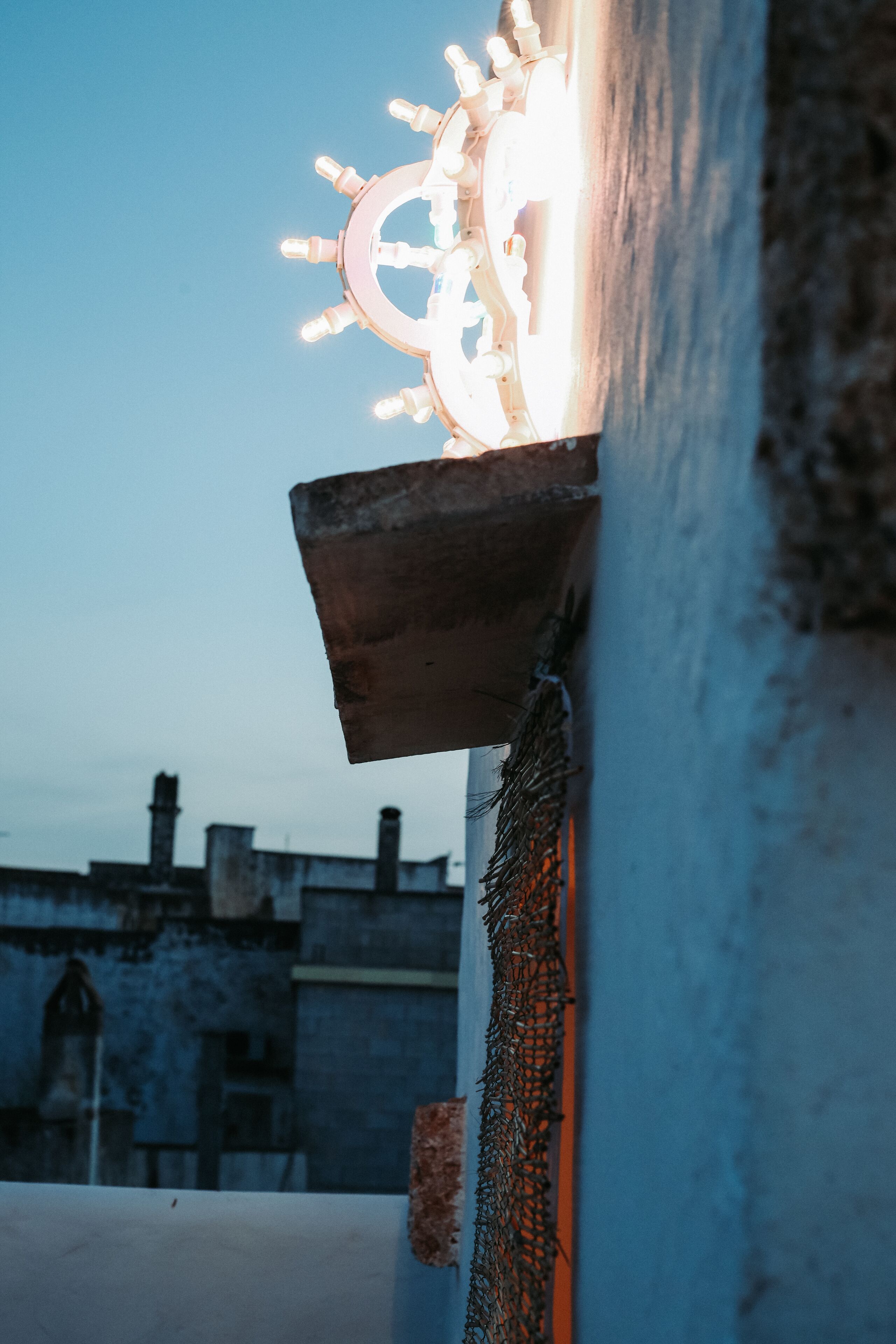 A building corner with a decorative light fixture and a metal mesh.