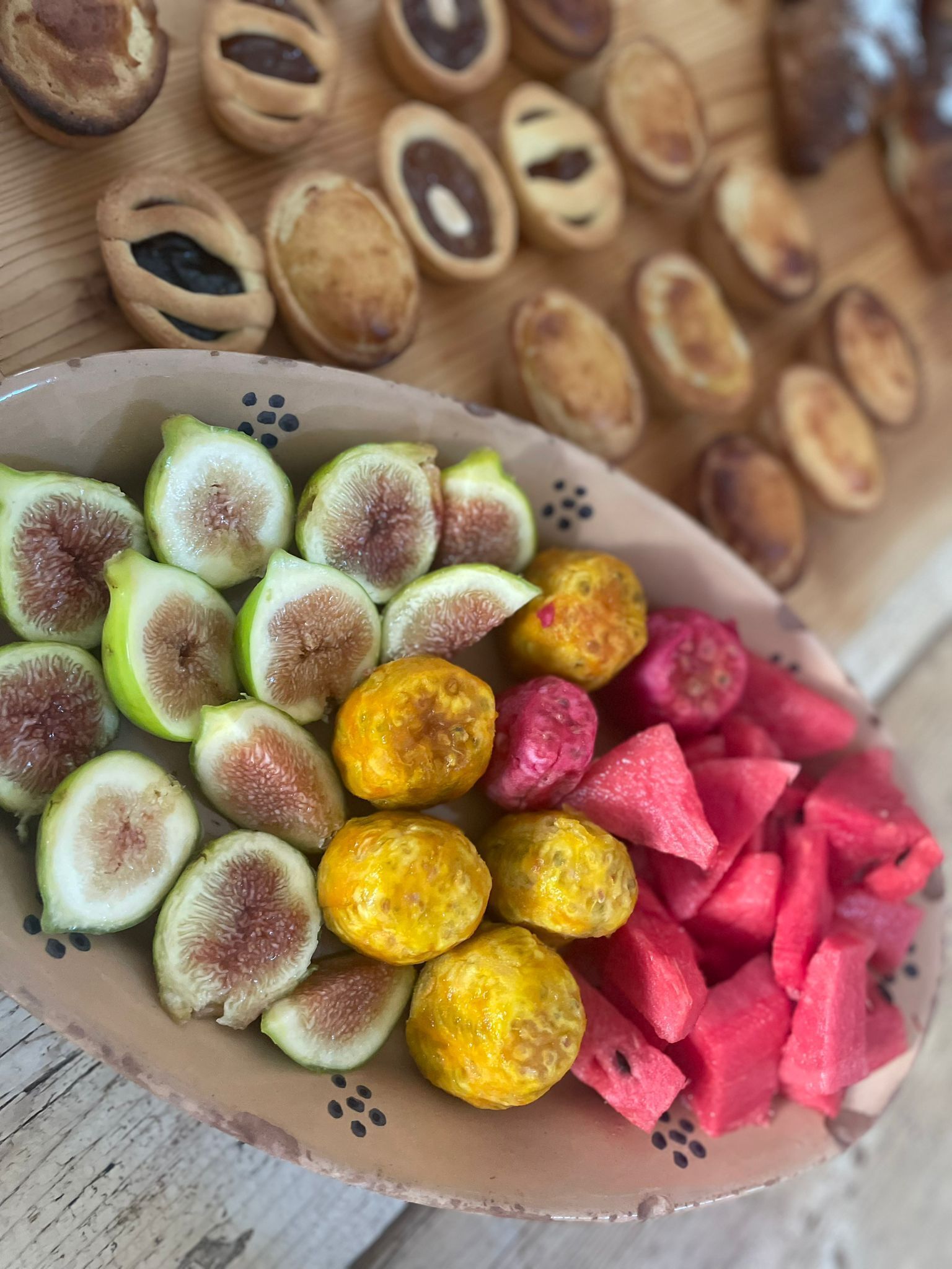 Ein Teller mit geschnittenen Feigen, gelben Früchten und Wassermelonenfruchtstücken.