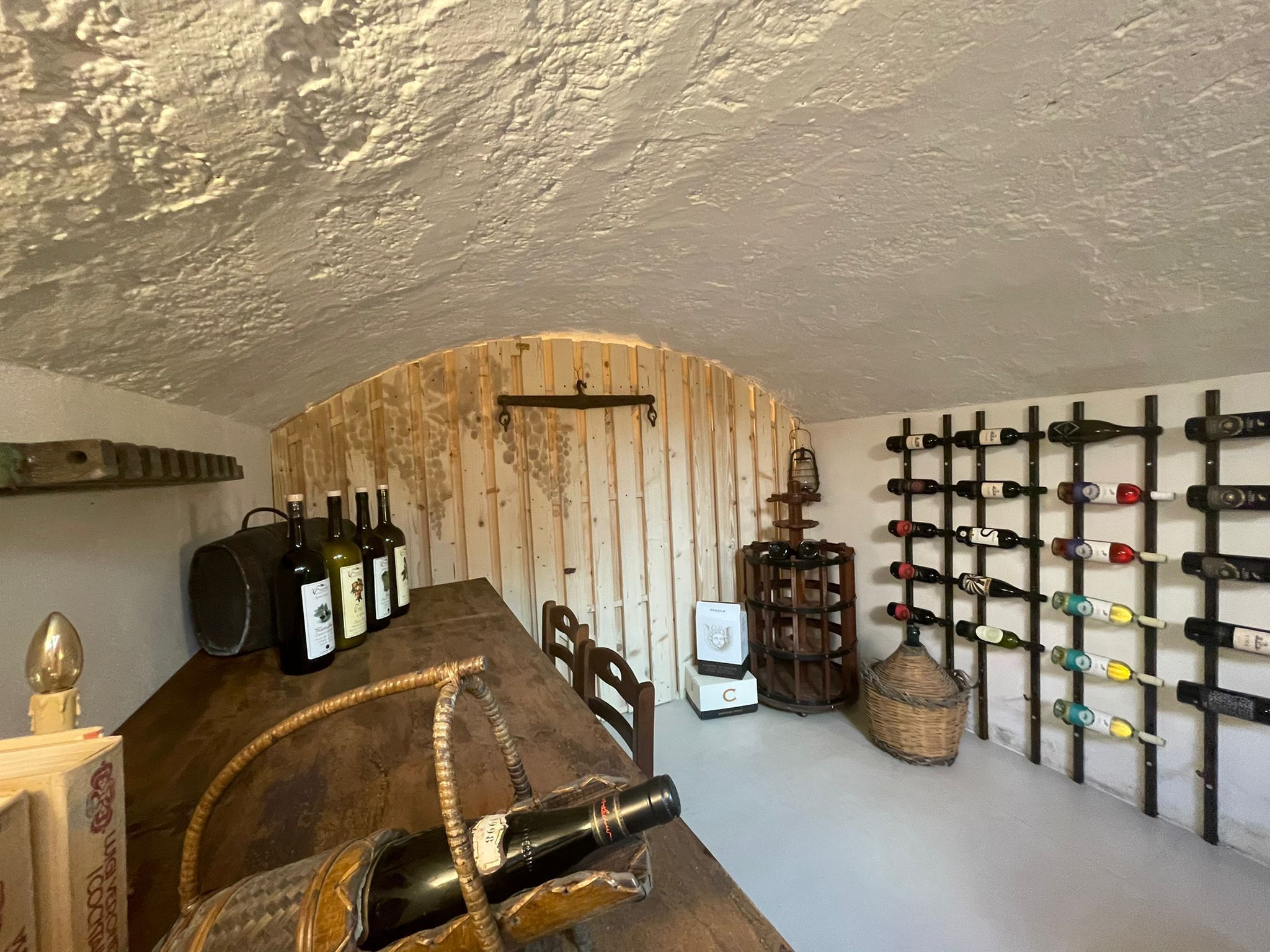 A rustic cellar with wooden walls, a wine rack, and a wooden barrel.