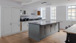 Een moderne keuken met witte kasten, een centraal eiland en een eetgedeelte met een houten tafel.