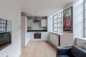 Een moderne keuken met witte kasten, een zwart aanrecht en een inbouwoven.