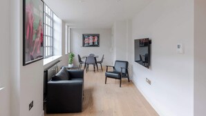 A modern living room with a sofa, a dining table with chairs, and a coffee machine. - Farringdon 1-Bed Apartment · Lift · Sleeps 3 (London)