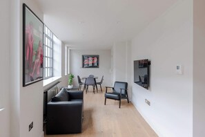 Ein modernes Wohnzimmer mit einer Couch, einem Esstisch mit Stühlen und einer Kaffeemaschine.