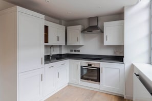 Eine moderne Küche mit weißen Schränken, einer Edelstahlspüle und einem Backofen von Bosch.