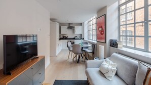 A modern living room with a TV, sofa, and dining area. - Clerkenwell 2-bed Apartment · Lift · Sleeps 4 (London)