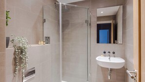 A modern bathroom with a glass-enclosed shower, a white sink, and a mirror. - Clerkenwell 2-bed Apartment · Lift · Sleeps 4 (London)