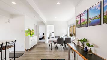 A modern interior with a dining area, kitchen, and a bedroom visible through an open door.
