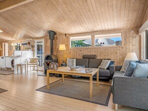 A cozy cabin interior with a wooden ceiling, a sofa, a dining table, and a kitchen area. - "Thrineke" - 600m from the sea by Interhome (Saltum)