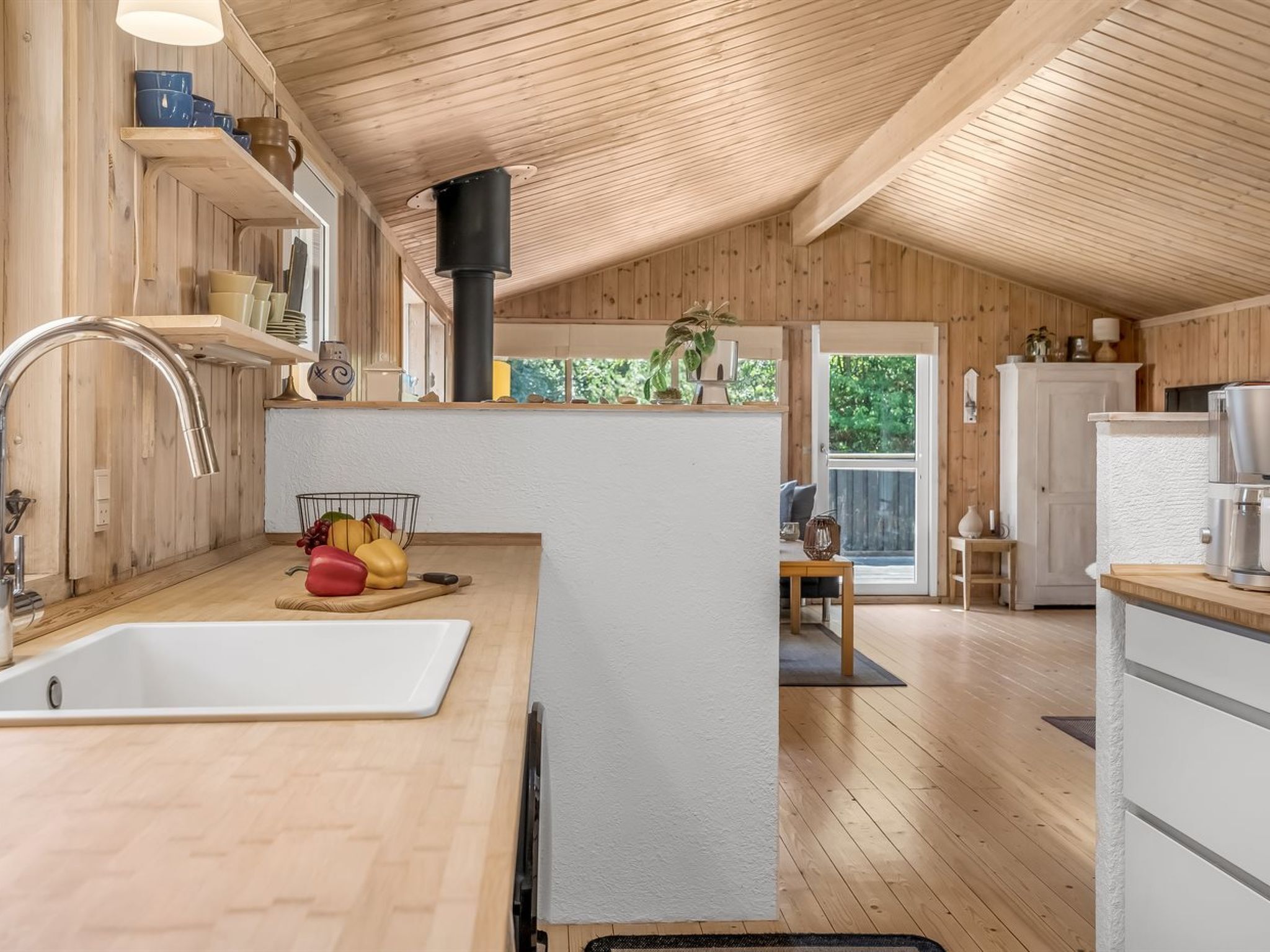 A modern kitchen with wooden walls, a white countertop, and a large window.