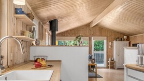 A modern kitchen with wooden walls, a white countertop, and a large window. - "Thrineke" - 600m from the sea by Interhome (Saltum)