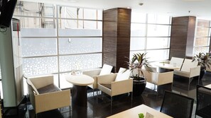 A modern lounge area with seating, a round table, and potted plants. - Studio One Thamrin Hotel (Jakarta)