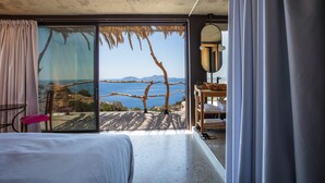 Un dormitorio con un amplio ventanal corredera que da a un balcón con vistas al mar.