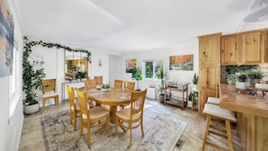 A spacious dining area with a round table and wooden chairs, surrounded by potted plants and a large rug. - SwimSpa | Sport Courts | Lake | Fishing | Firepit (Highland Lake)