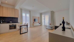 Een moderne keuken met houten kastjes, een ingebouwde oven en een eethoek met een tafel en stoelen.