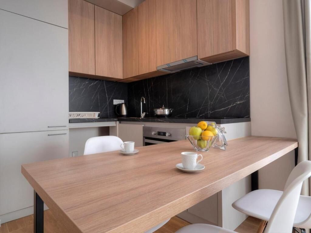 A modern kitchen with wooden cabinets, a marble backsplash, and a dining table with chairs.